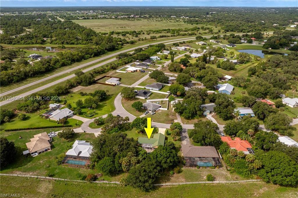 An aerial view shows a residential house with a green roof surrounded by trees — 4559 Springview Cir, La Belle FL 33935, LA BELLE, FL