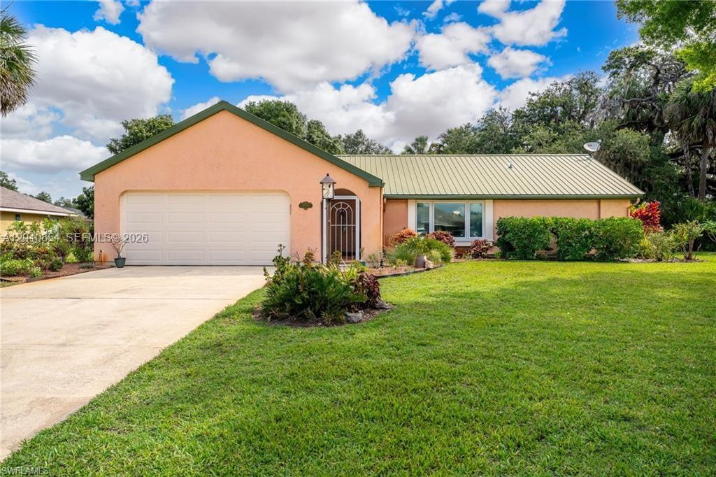 A single-story peach-colored house with a metal roof and a two-car garage — 4559 Springview Cir, La Belle FL 33935, LA BELLE, FL
