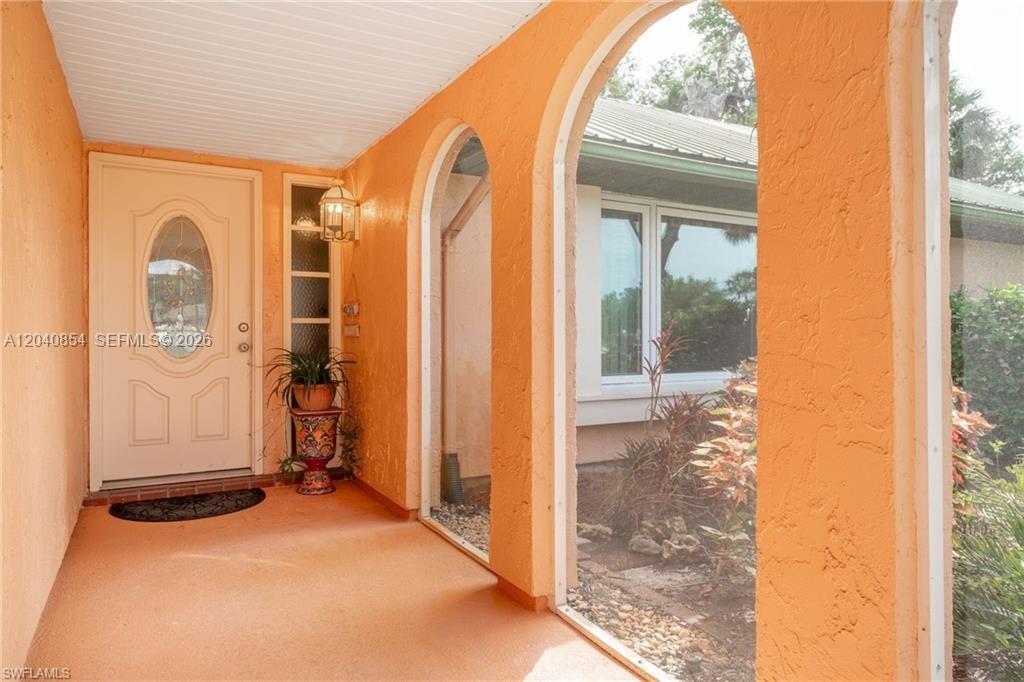 An orange stucco entryway features arched openings, a front door, and a potted plant — 4559 Springview Cir, La Belle FL 33935, LA BELLE, FL