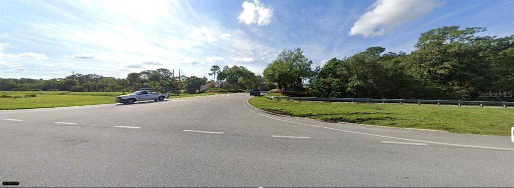 A wide asphalt road curves past a grassy area with trees and a parked truck — 5114 HOMELAND ROAD, WELLINGTON, FL