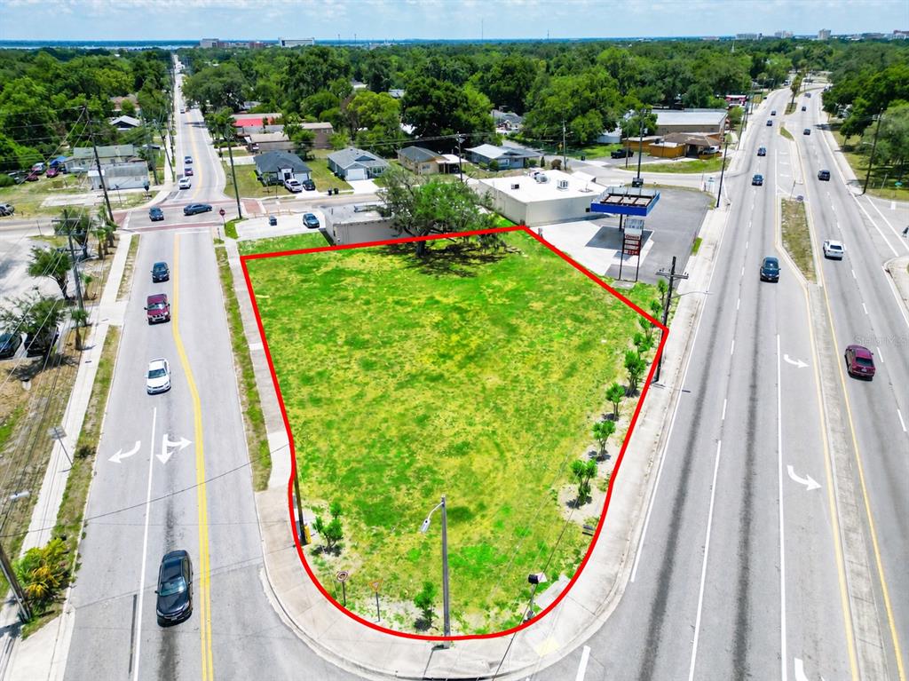 An aerial view shows a vacant, grass-covered triangular lot situated between two busy roads — 0 10TH STREET W, LAKELAND, FL