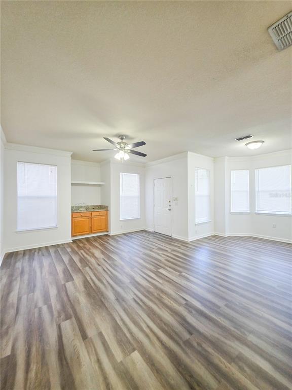 A living room features wood-look flooring, a ceiling fan, and a built-in wooden cabinet — 10431 VILLA VIEW CIRCLE UNIT 10431, TAMPA, FL