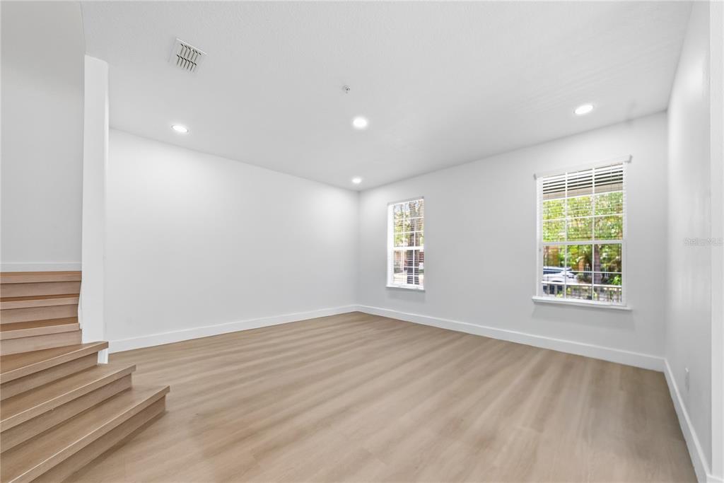 A modern kitchen with white cabinets, wood-slat accents, and a staircase leading to an upper level — 10359 LAKE DISTRICT LANE UNIT 58B, ORLANDO, FL