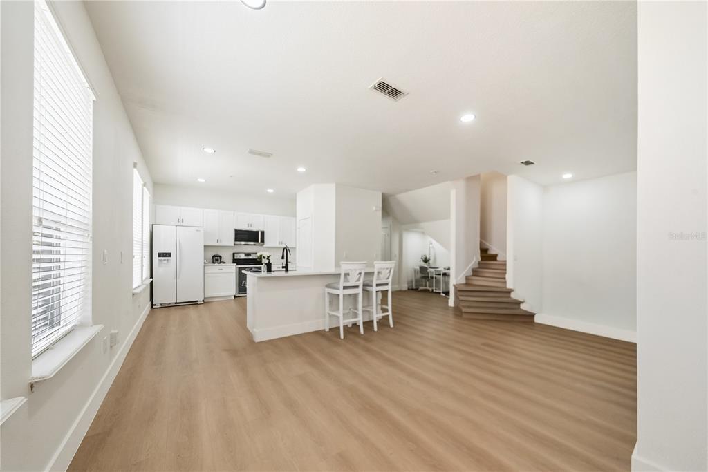 A modern living room features light wood flooring, a sectional sofa, and a wall-mounted television — 10359 LAKE DISTRICT LANE UNIT 58B, ORLANDO, FL