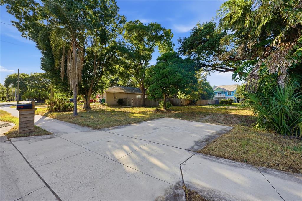 A concrete driveway leads to a grassy lot with mature trees and a wooden fence — 2929 W AVERILL AVENUE, TAMPA, FL