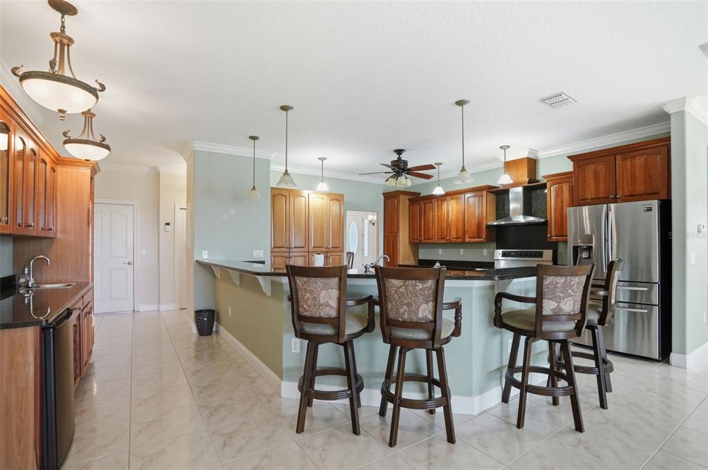 A kitchen with wood cabinets, stainless steel appliances, a breakfast bar, and tile flooring — 9011 FOXDALE LANE, SPRING HILL, FL