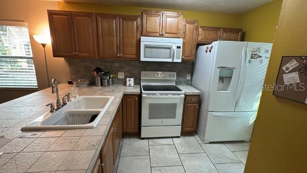 A kitchen features wooden cabinets, a tiled countertop, a white stove, and a white refrigerator — 4643 SUMMERWIND DRIVE UNIT 22, SARASOTA, FL