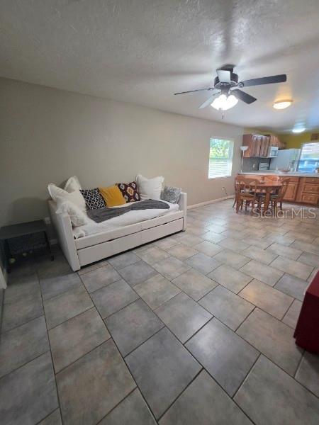 A living room with tile flooring, a daybed, and an open kitchen in the background — 4643 SUMMERWIND DRIVE UNIT 22, SARASOTA, FL