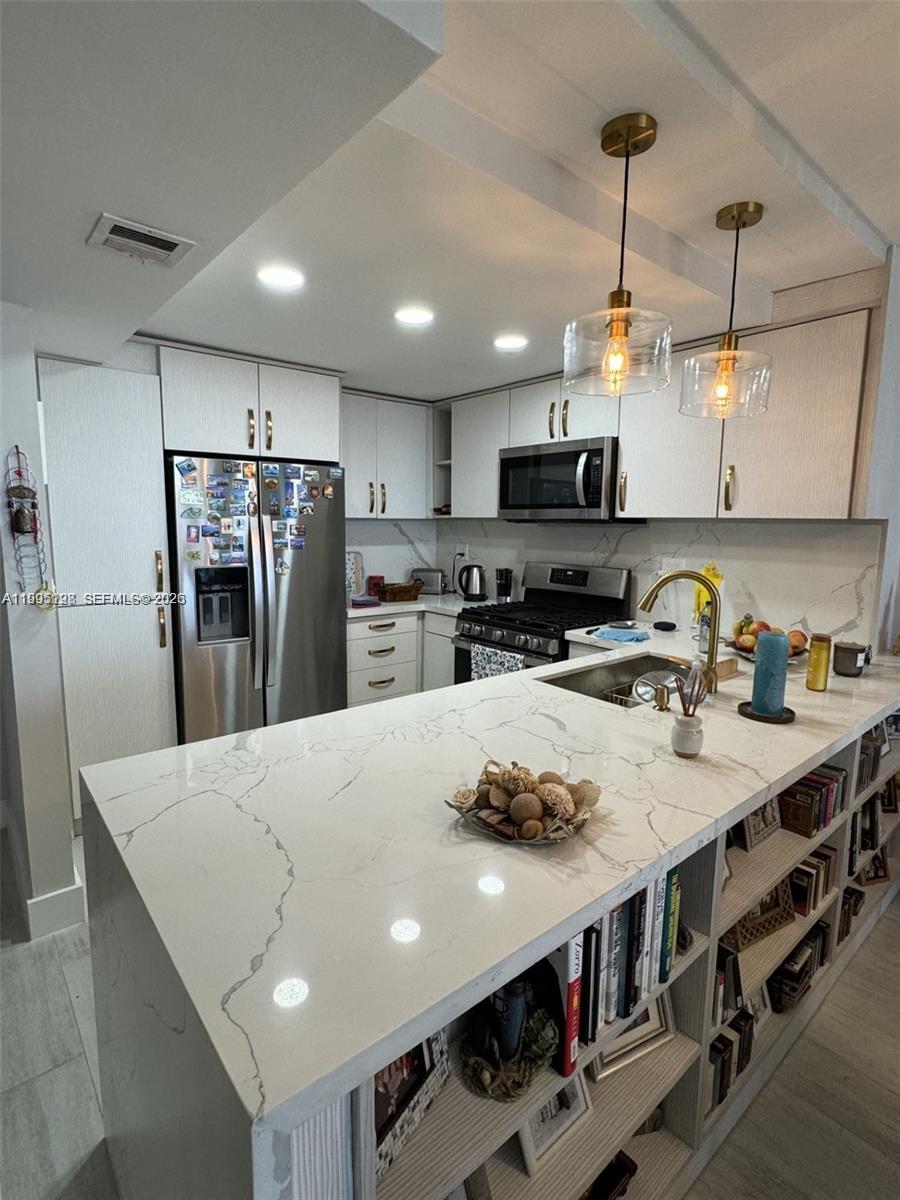 A modern kitchen features white cabinets, marble-patterned countertops, and a breakfast bar with open shelving — 2030 S Ocean Dr # 815, Hallandale Beach FL 33009, HALLANDALE BEACH, FL