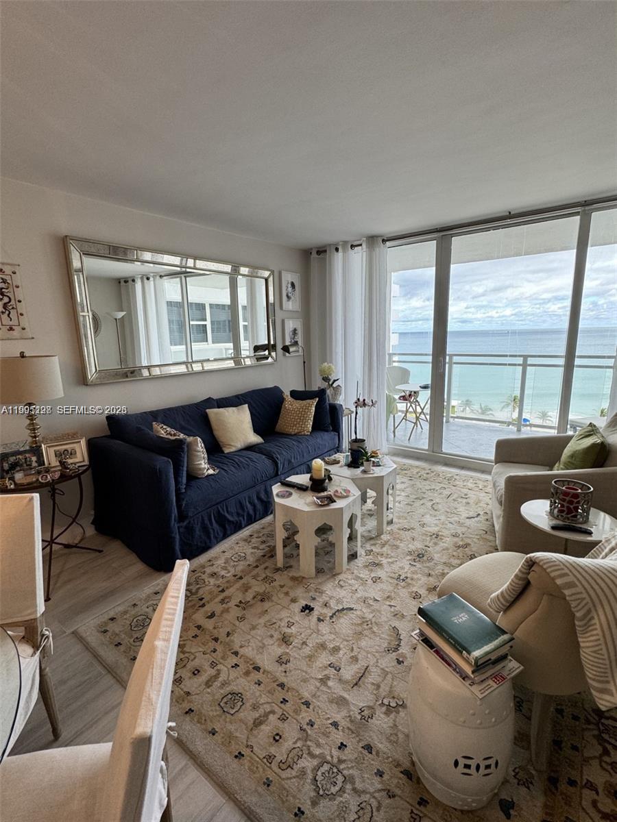 A living room features a navy sofa, patterned rug, and floor-to-ceiling windows overlooking the ocean — 2030 S Ocean Dr # 815, Hallandale Beach FL 33009, HALLANDALE BEACH, FL