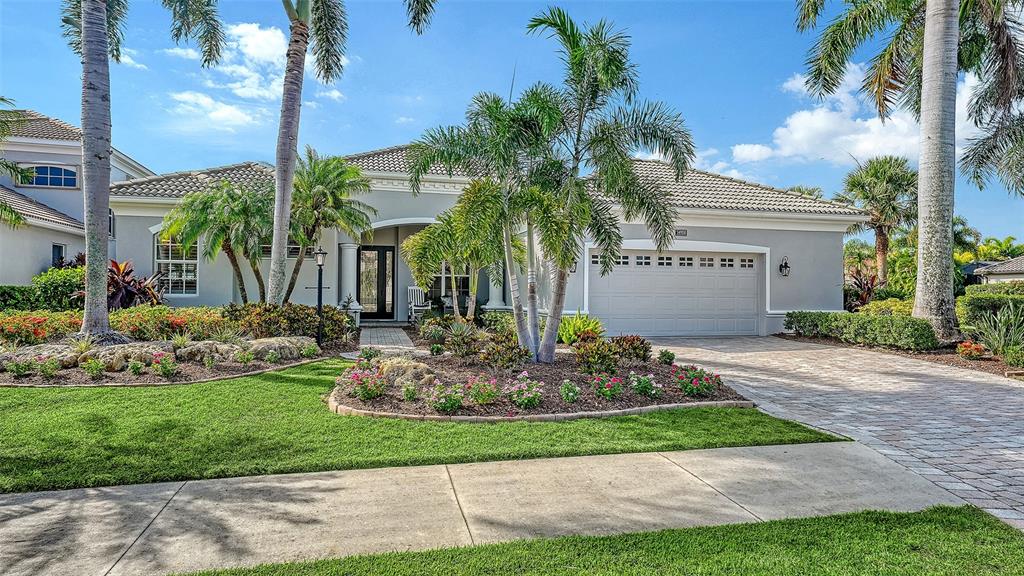 A single-story gray house with a tiled roof, palm trees, and a paved driveway — 14908 BOWFIN TERRACE, LAKEWOOD RANCH, FL