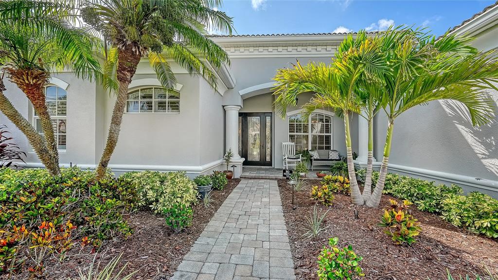 A paved walkway leads to the front entrance of a single-story house with palm trees — 14908 BOWFIN TERRACE, LAKEWOOD RANCH, FL