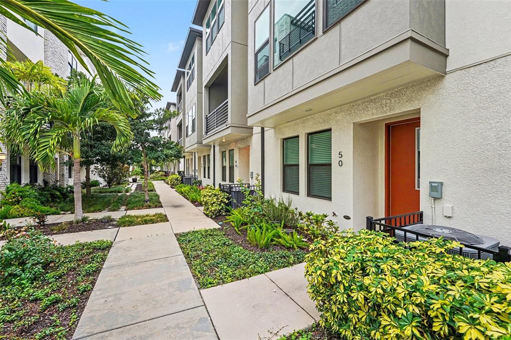 A sidewalk leads past a modern townhouse with an orange door and landscaped front yard — 2511 N GRADY AVENUE UNIT 50, TAMPA, FL
