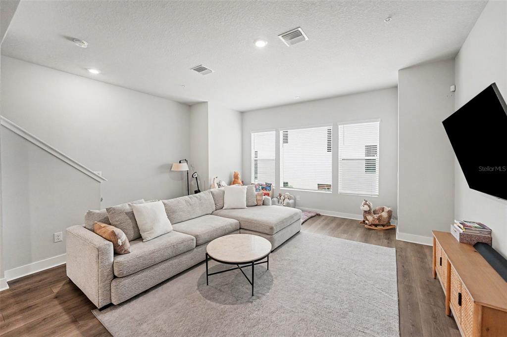 A living room features a gray sectional sofa, a round coffee table, and a wall-mounted television — 2511 N GRADY AVENUE UNIT 50, TAMPA, FL