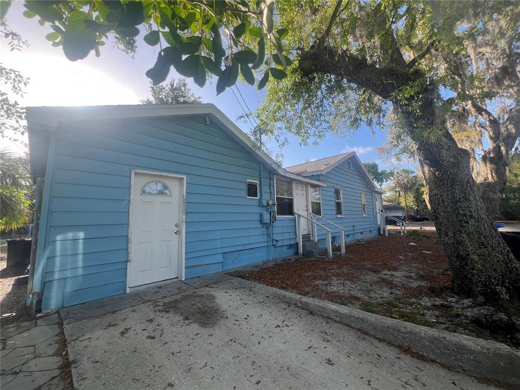 A blue, single-story house with white trim and a concrete driveway under a large tree — 2575 18TH AVENUE S, ST PETERSBURG, FL
