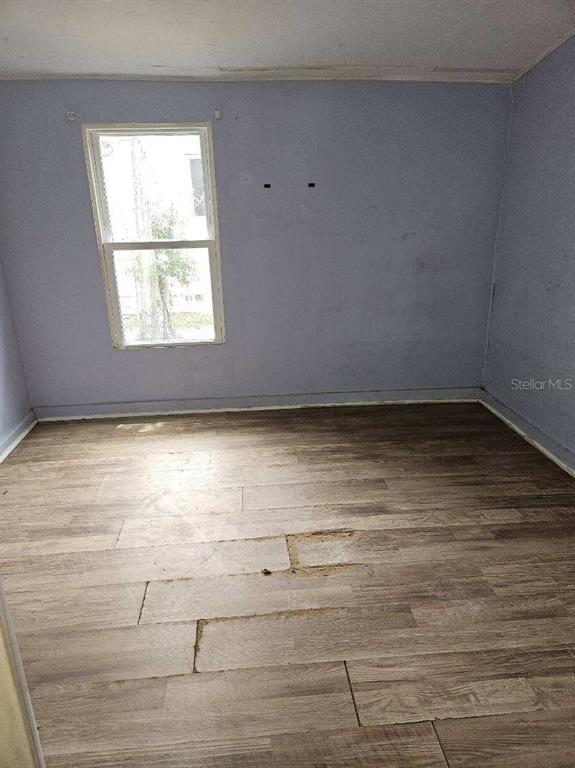 An empty room with light purple walls, a single window, and wood-look flooring — 2575 18TH AVENUE S, ST PETERSBURG, FL