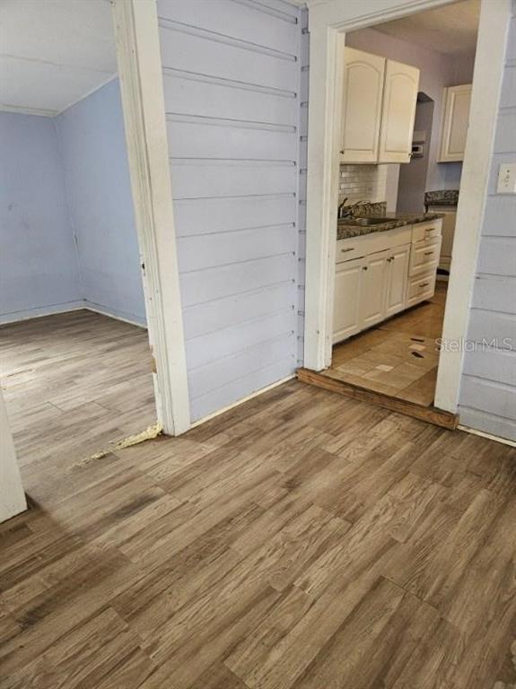 A view through a doorway shows a kitchen with white cabinets and wood-look flooring — 2575 18TH AVENUE S, ST PETERSBURG, FL