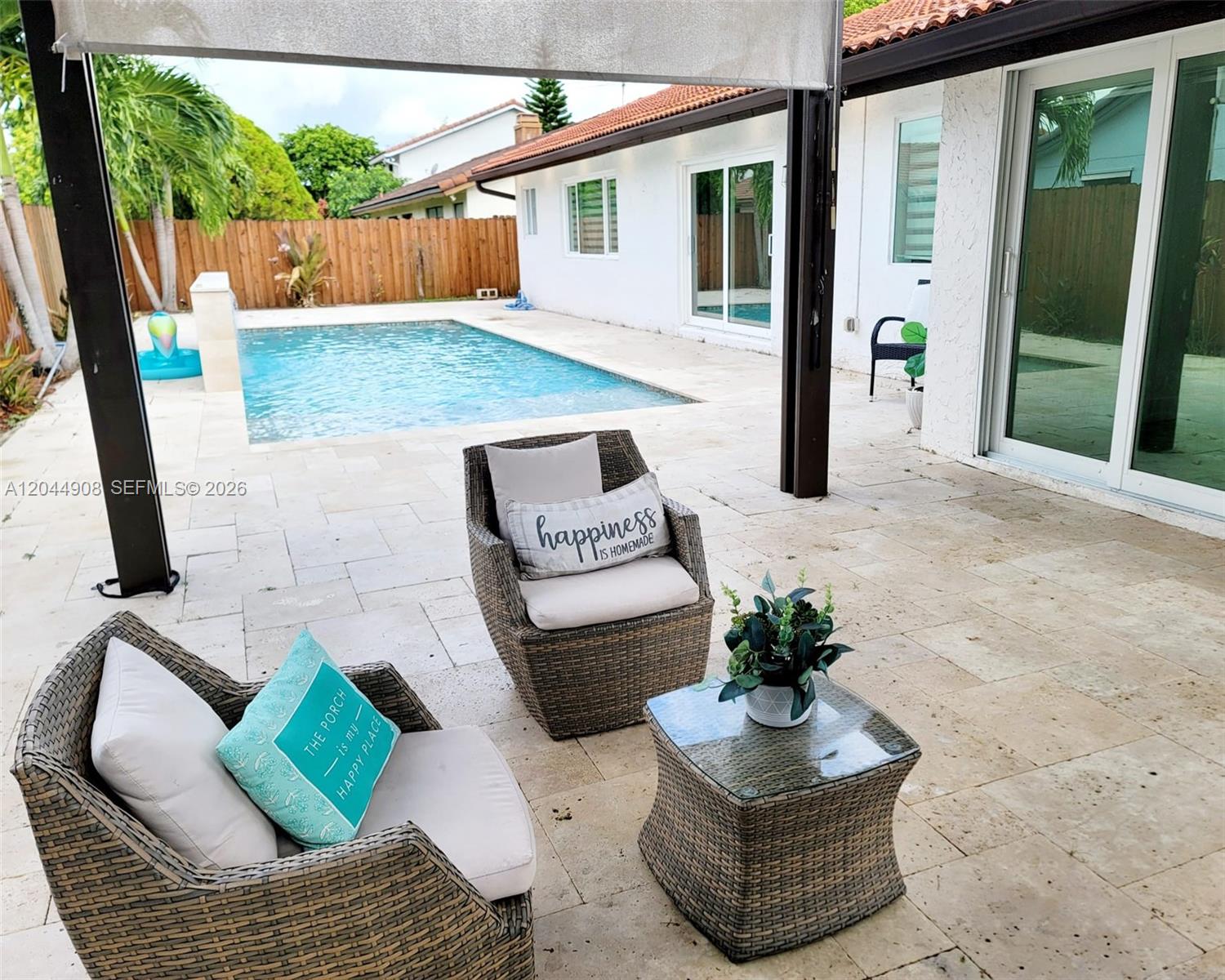 A patio with wicker chairs, a small table, and a swimming pool in the backyard — 6324 NW 201st Ln, Hialeah FL 33015, HIALEAH, FL