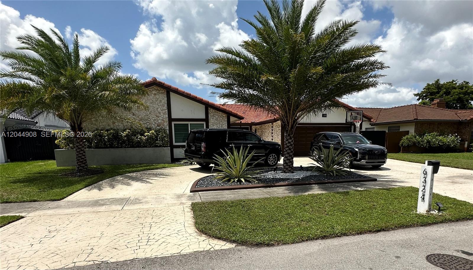 A single-story house with a stone facade, two palm trees, and two parked SUVs — 6324 NW 201st Ln, Hialeah FL 33015, HIALEAH, FL