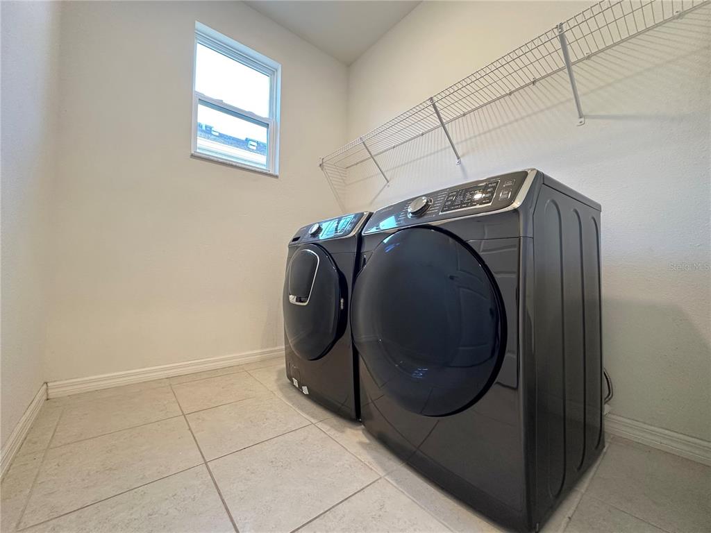 A laundry room features dark gray appliances, tile flooring, and a white wire shelf — 177 BELLA VERANO WAY, DAVENPORT, FL