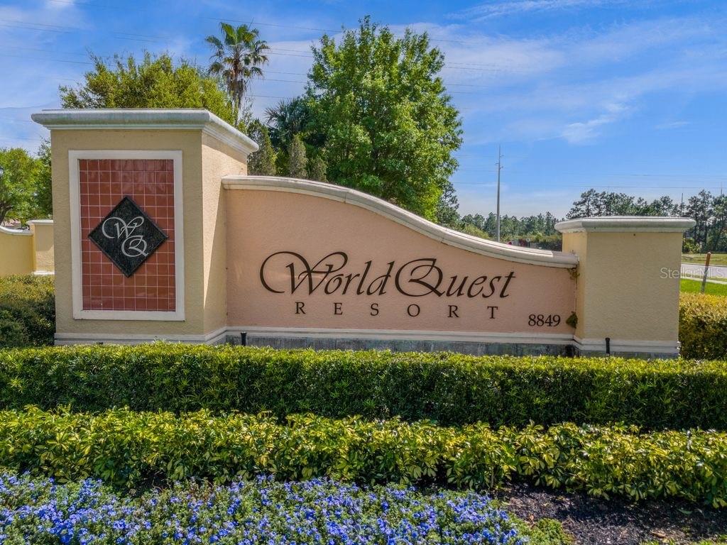A beige stucco monument sign for World Quest Resort stands behind a manicured hedge — 8762 WORLDQUEST BOULEVARD UNIT 6102, ORLANDO, FL
