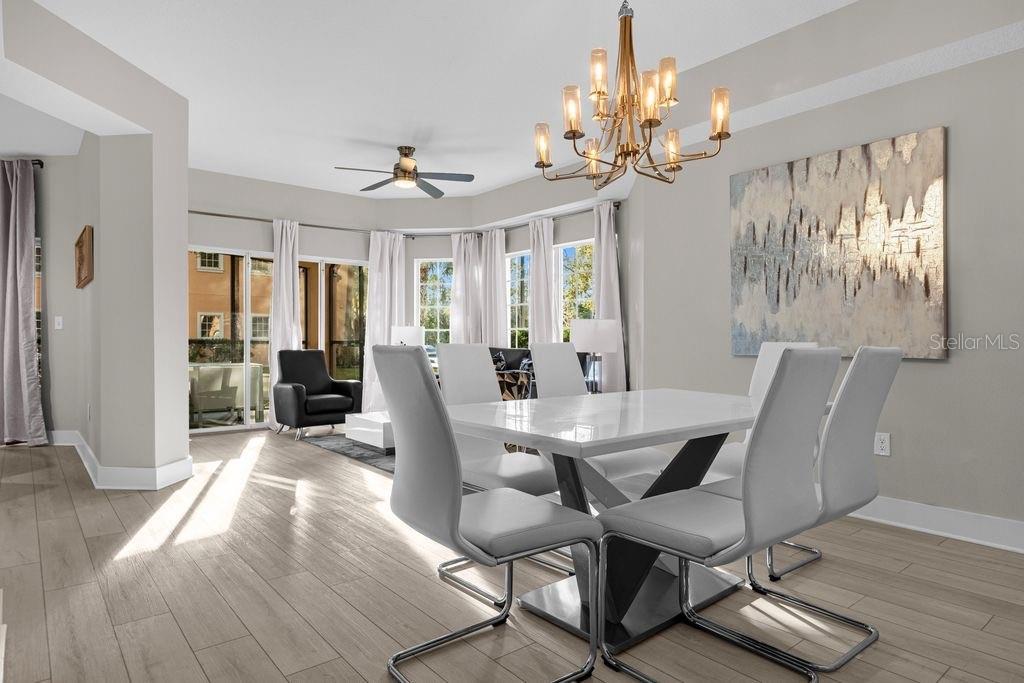 A dining area with a white table, modern chairs, a chandelier, and wood-look tile flooring — 8762 WORLDQUEST BOULEVARD UNIT 6102, ORLANDO, FL