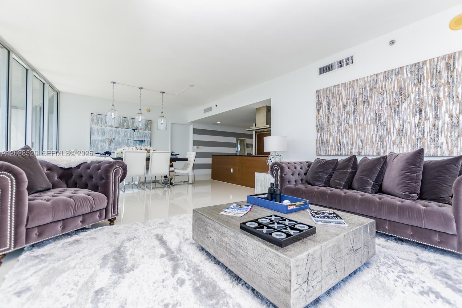 A living room features two tufted velvet sofas, a large coffee table, and an adjacent dining area — 495 Brickell Ave # 4901, Miami FL 33131, MIAMI, FL