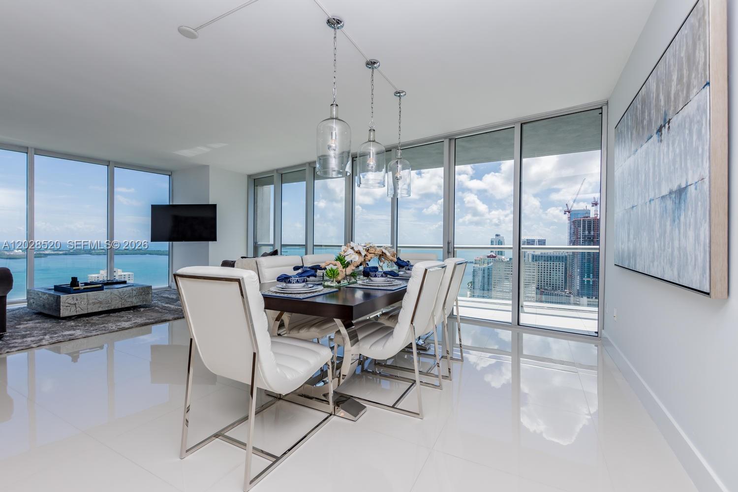 A modern dining room features a dark table, white chairs, and floor-to-ceiling windows with views — 495 Brickell Ave # 4901, Miami FL 33131, MIAMI, FL