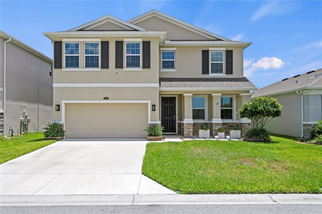 A two-story suburban house features a tan exterior, a two-car garage, and a front lawn — 3288 TUCSON WIND PLACE, ODESSA, FL