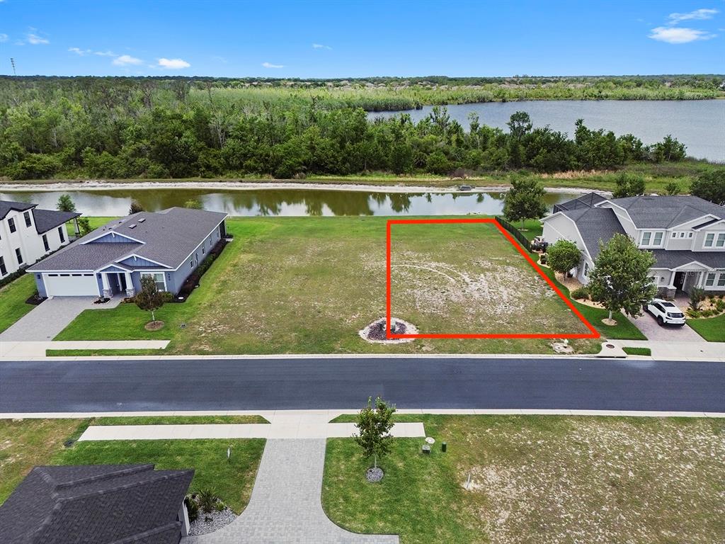 An aerial view shows a vacant residential lot outlined in red between two houses — 497 ADAMS VIEW LANE, AUBURNDALE, FL