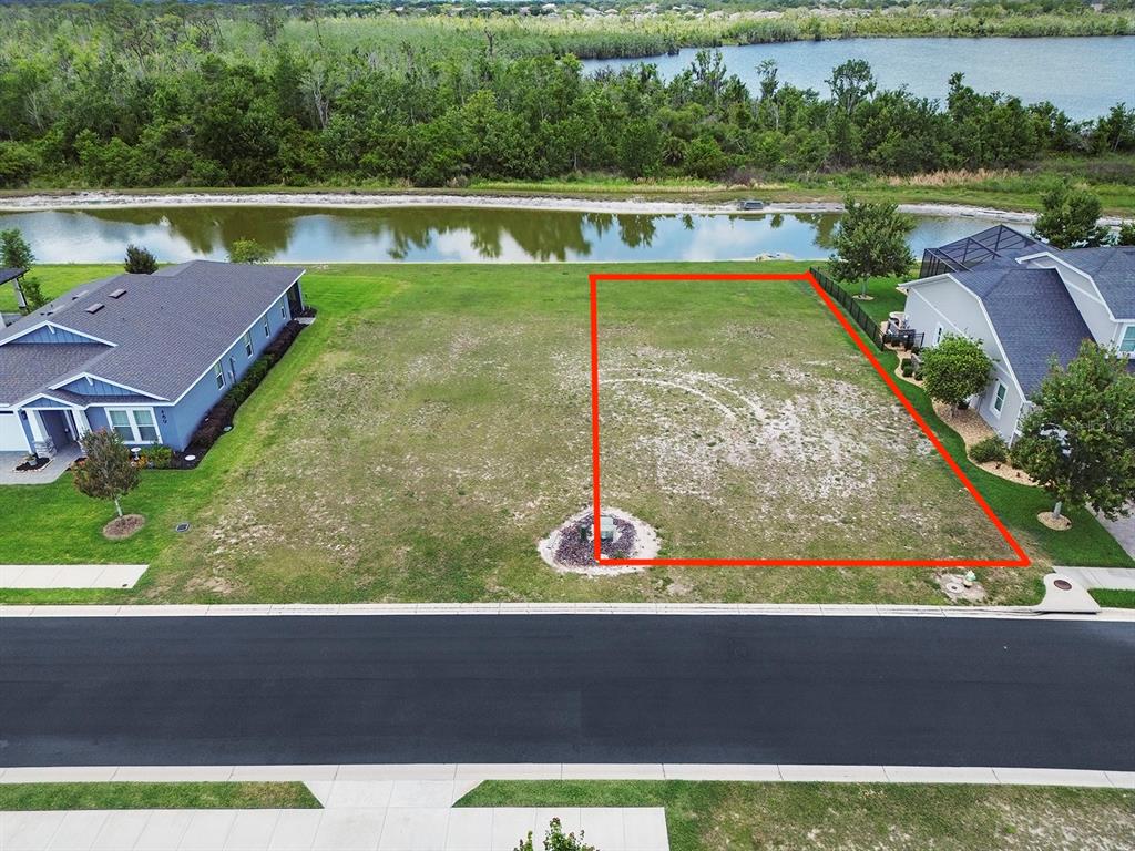 An aerial view shows a vacant residential lot outlined in red next to a house — 497 ADAMS VIEW LANE, AUBURNDALE, FL