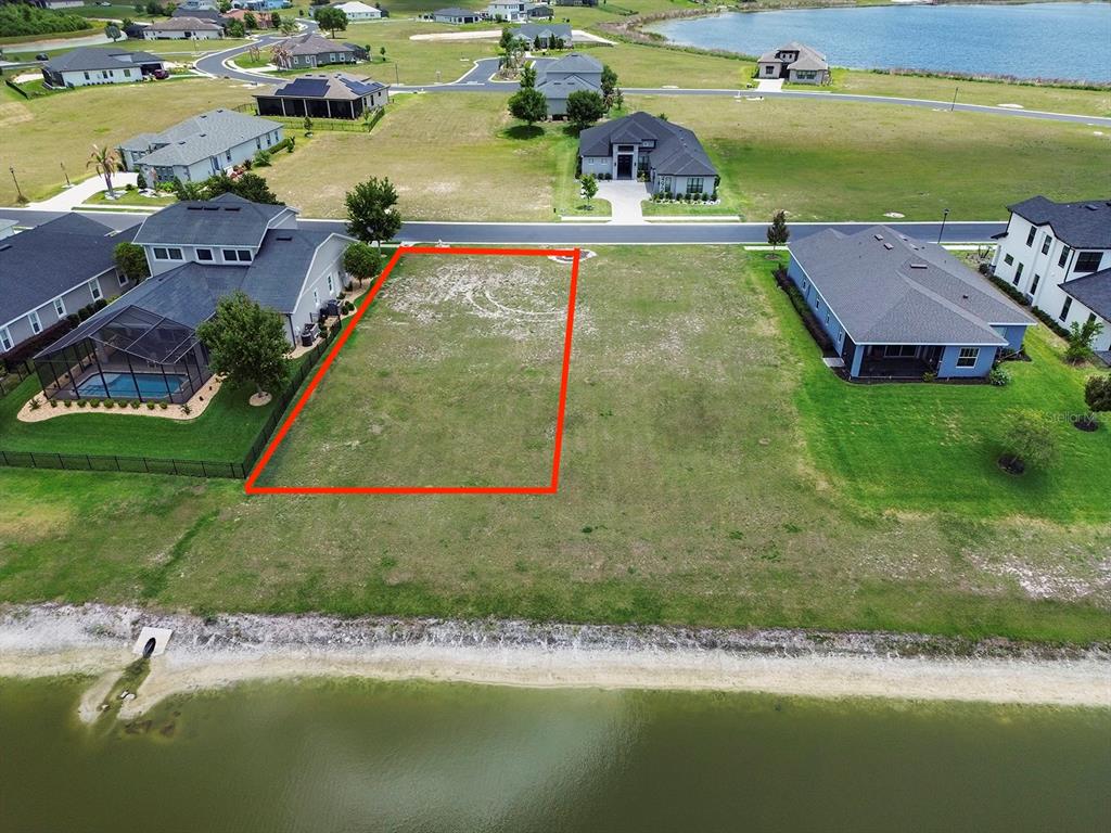 An aerial view shows a vacant rectangular lot outlined in red between two residential houses — 497 ADAMS VIEW LANE, AUBURNDALE, FL