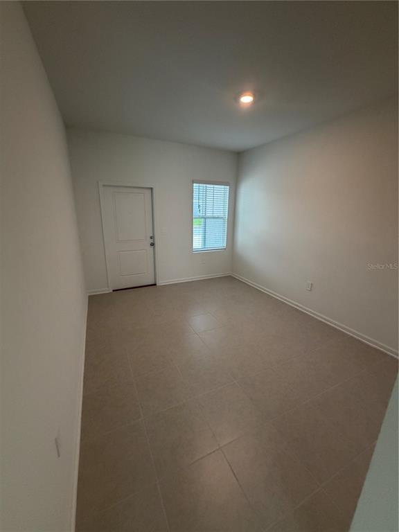 An empty room with light-colored tile flooring, white walls, a single window, and one door — 6077 ZEN WAY, CLERMONT, FL