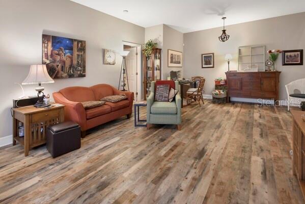 A living room features wood-look flooring, an orange sofa, a green armchair, and wooden furniture — 207 VICTORIA COMMONS BOULEVARD, DELAND, FL