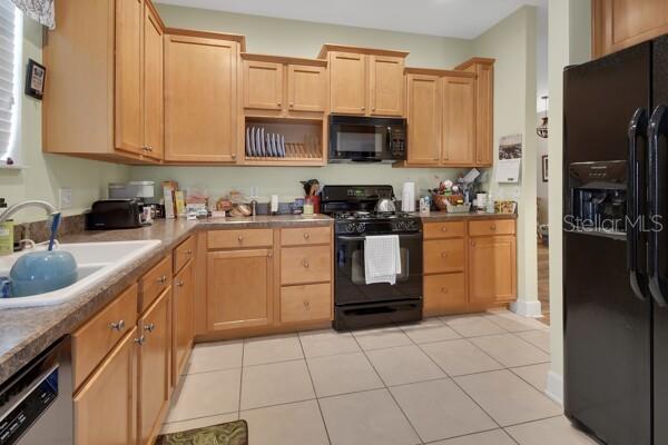 A kitchen with light wood cabinets, black appliances, and tan tile flooring — 207 VICTORIA COMMONS BOULEVARD, DELAND, FL