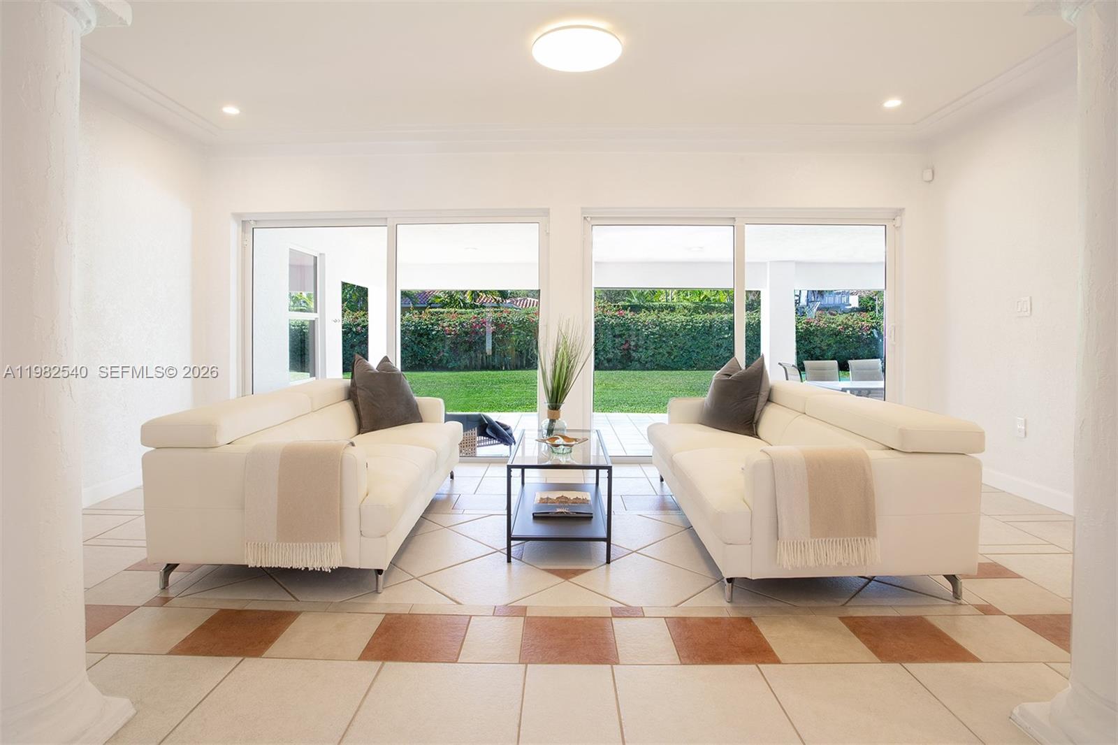 A living room features two white sofas facing each other on a tiled floor — 100 SW 26th Rd, Miami FL 33129, MIAMI, FL