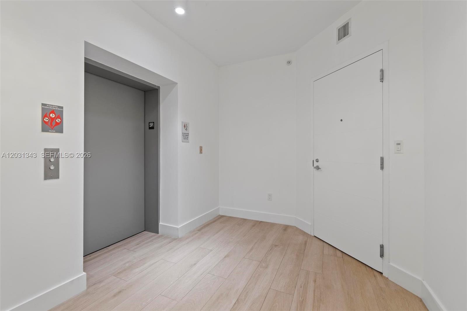 A hallway features light wood-look flooring, a grey elevator door, and a white entry door — NORTH MIAMI BEACH, FL