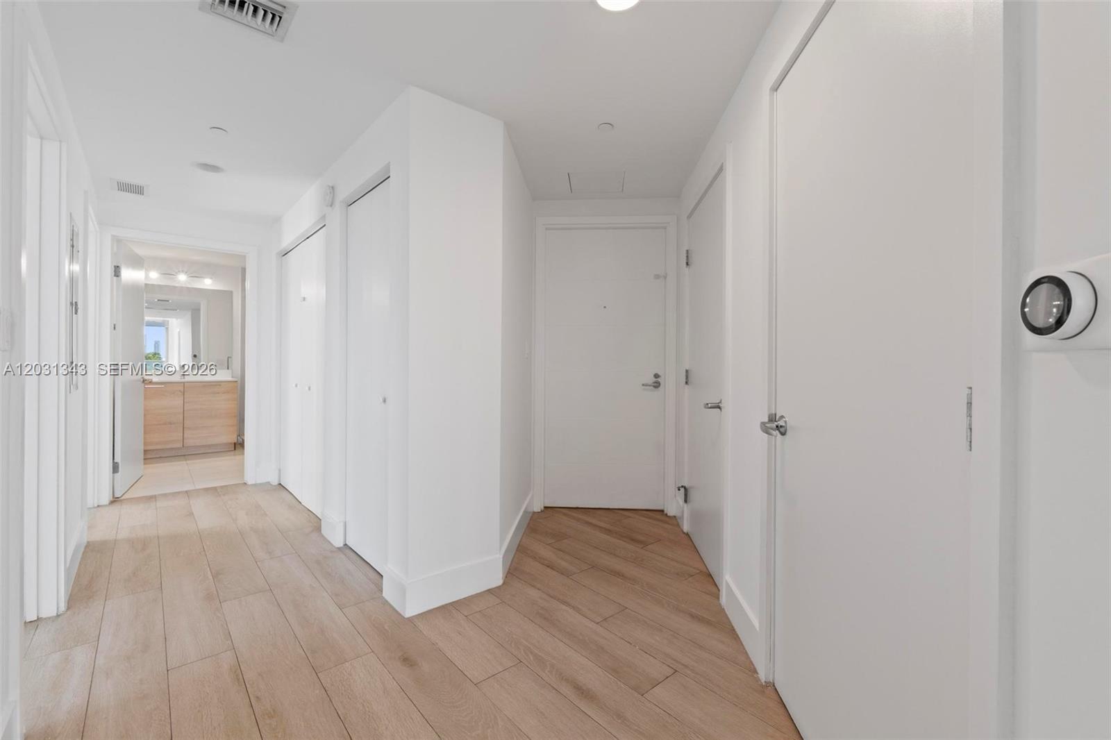A bright hallway features light wood-look tile flooring and multiple white doors — NORTH MIAMI BEACH, FL