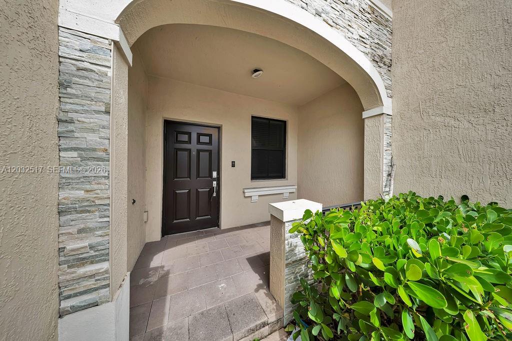 The exterior entrance features a dark door, a stone-accented archway, and a small porch — 23130 SW 127th Ct, Miami FL 33170, MIAMI, FL