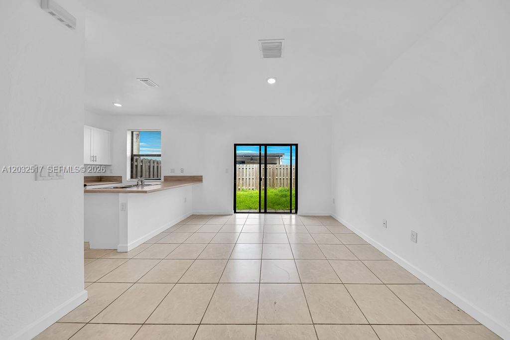 A bright, open-concept kitchen and living area features white walls and light-colored floor tiles — 23130 SW 127th Ct, Miami FL 33170, MIAMI, FL