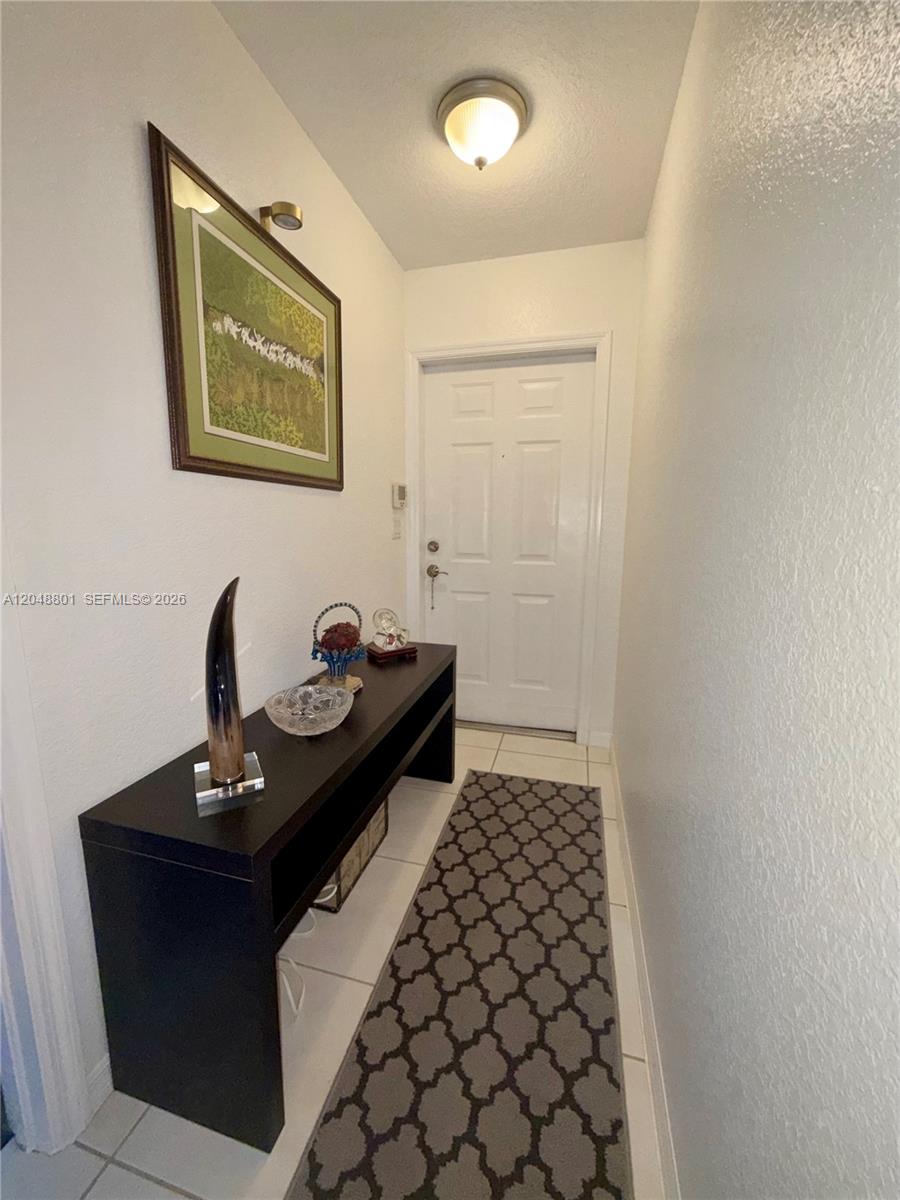 A narrow entryway features white walls, a dark console table, and a patterned runner rug — 11301 SW 17th Ct, Miramar FL 33025, MIRAMAR, FL