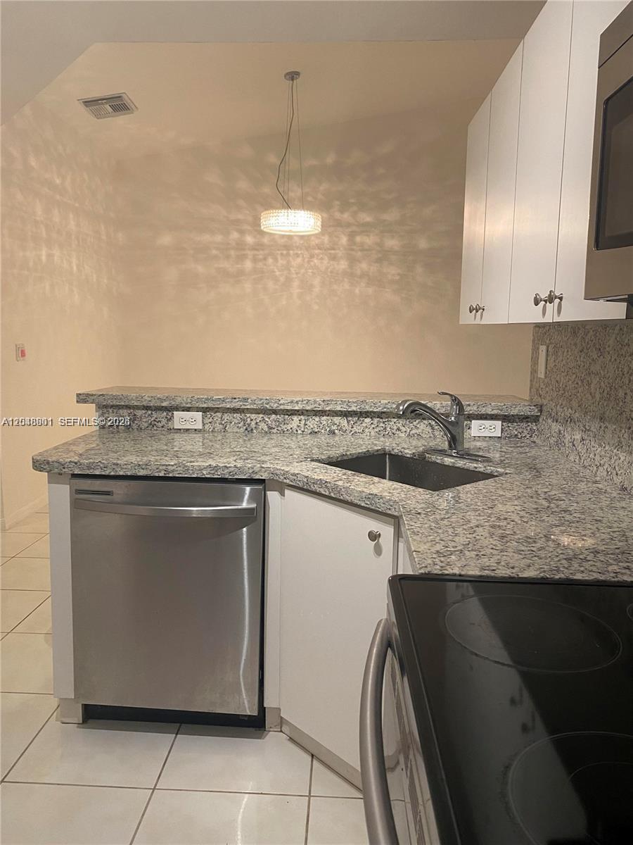 A kitchen features white cabinets, granite countertops, a stainless steel dishwasher, and a corner sink — 11301 SW 17th Ct, Miramar FL 33025, MIRAMAR, FL