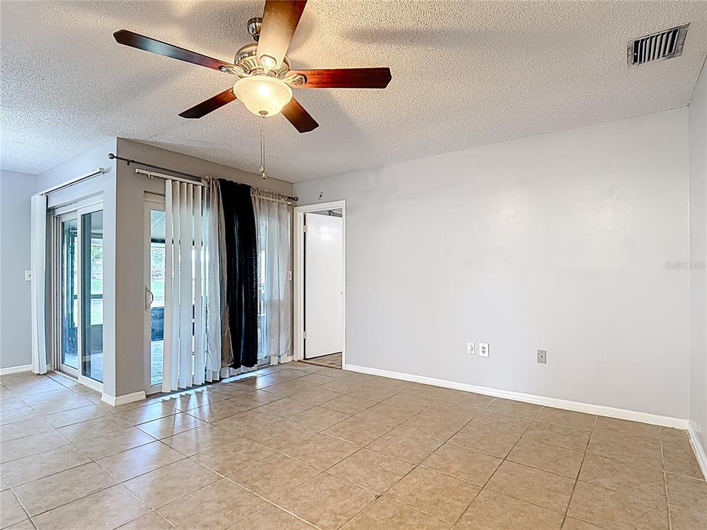 A room with tile flooring, a ceiling fan, sliding glass doors, and a doorway — 571 HUNTER CIRCLE, KISSIMMEE, FL