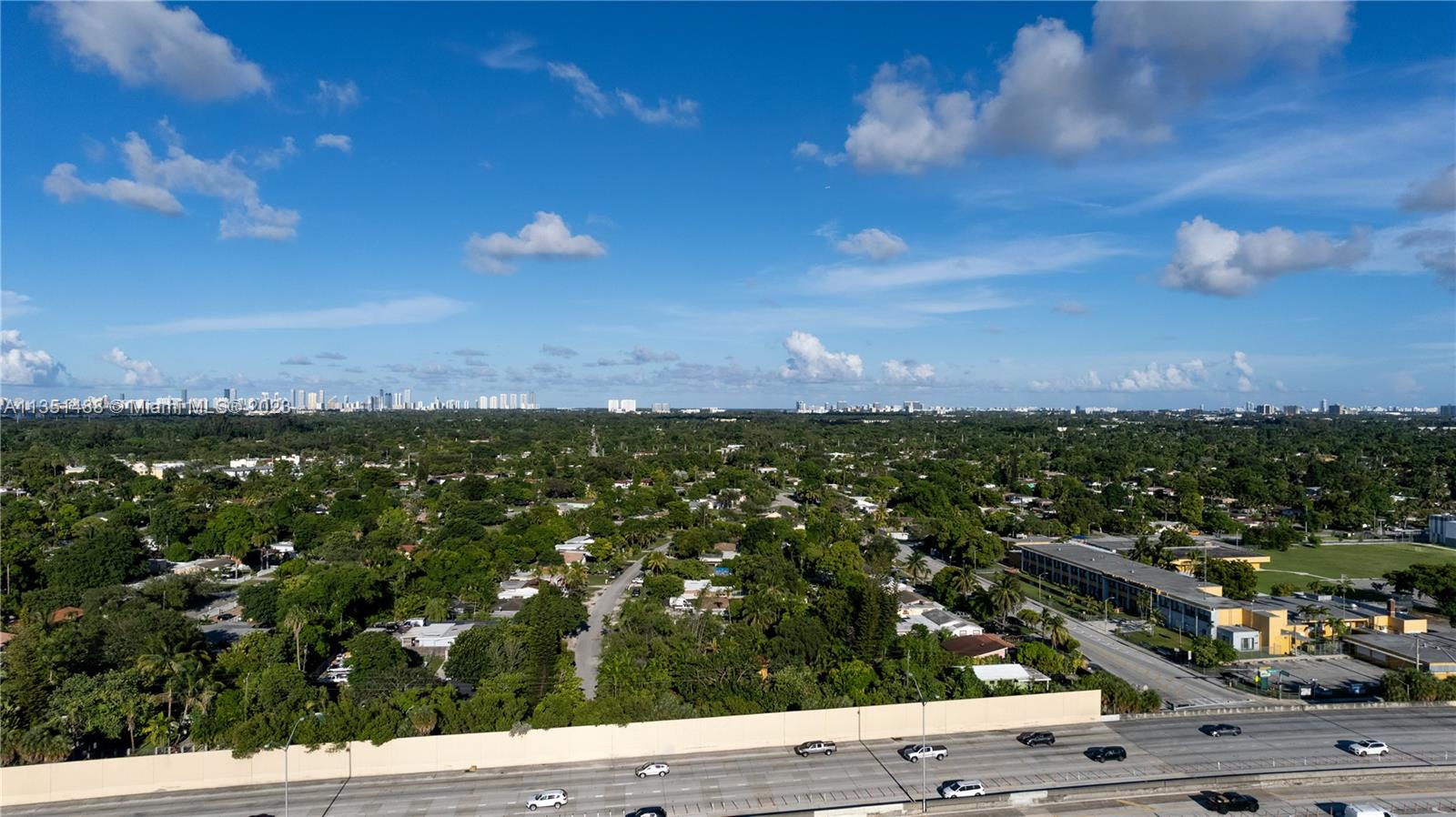 An elevated view shows a highway in the foreground and a residential area with trees — 665 NW 151st St, Miami FL 33169, MIAMI, FL