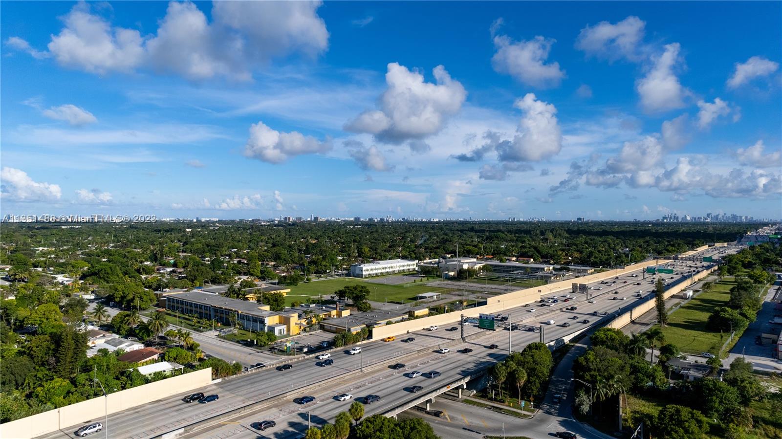An aerial view shows a multi-lane highway running alongside a school campus and green space — 665 NW 151st St, Miami FL 33169, MIAMI, FL