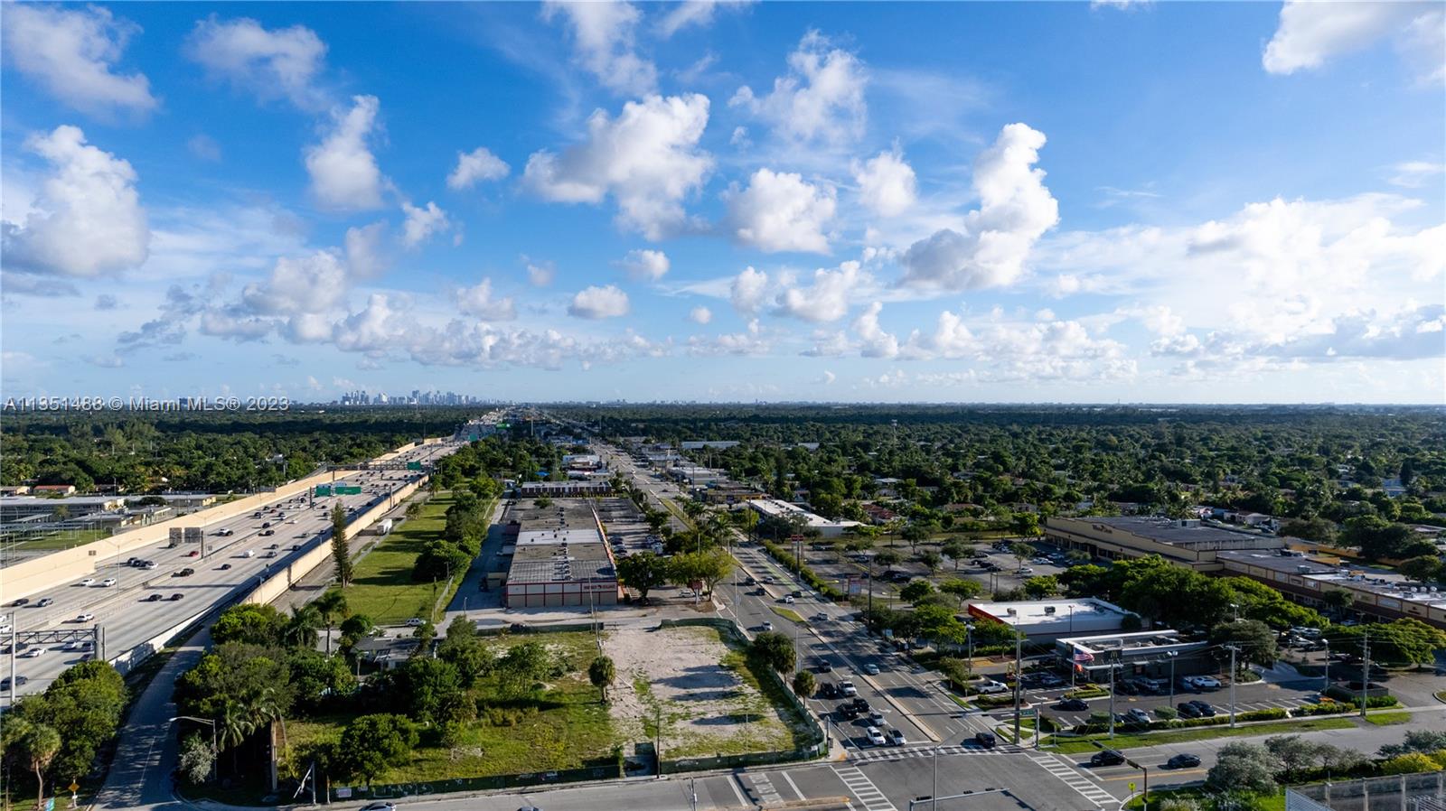 An aerial view shows a highway running parallel to a commercial area with parking lots — 665 NW 151st St, Miami FL 33169, MIAMI, FL