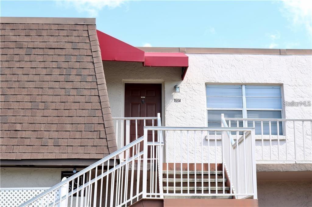 An exterior view shows a brown door numbered 207, a red awning, and white stairs — 9101 W HILLSBOROUGH AVENUE UNIT I207, TAMPA, FL