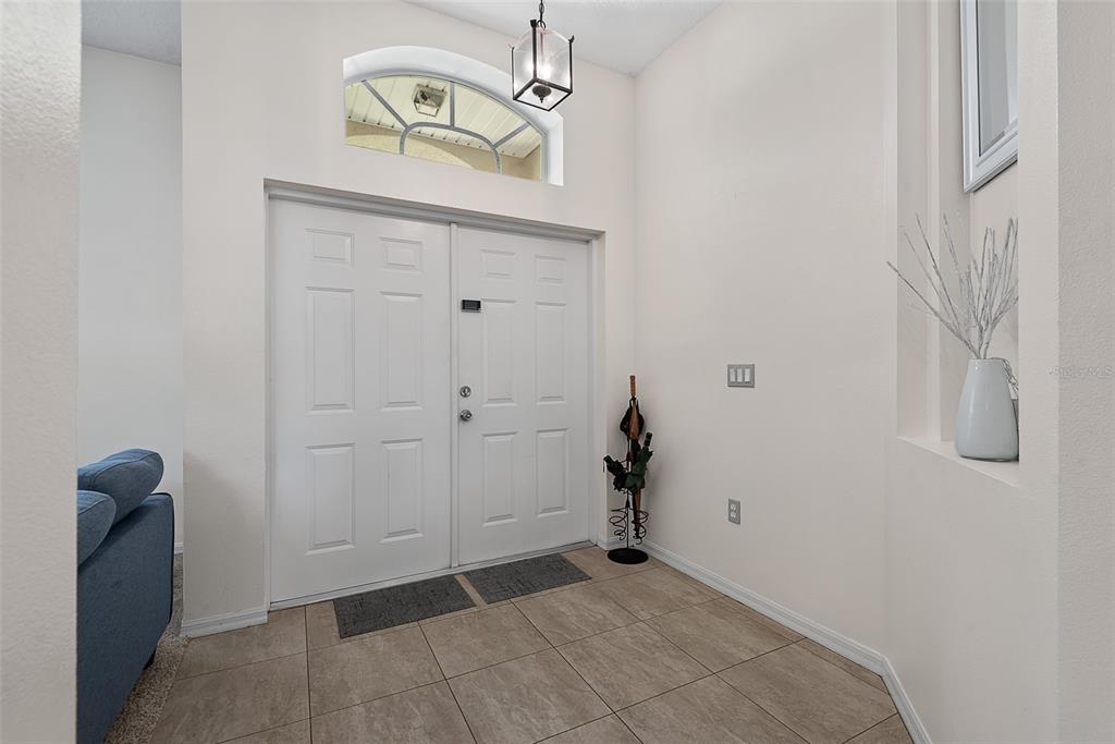 A tiled entryway features double white front doors, a transom window, and a hanging lantern — 3 RUSSMAN LANE, PALM COAST, FL