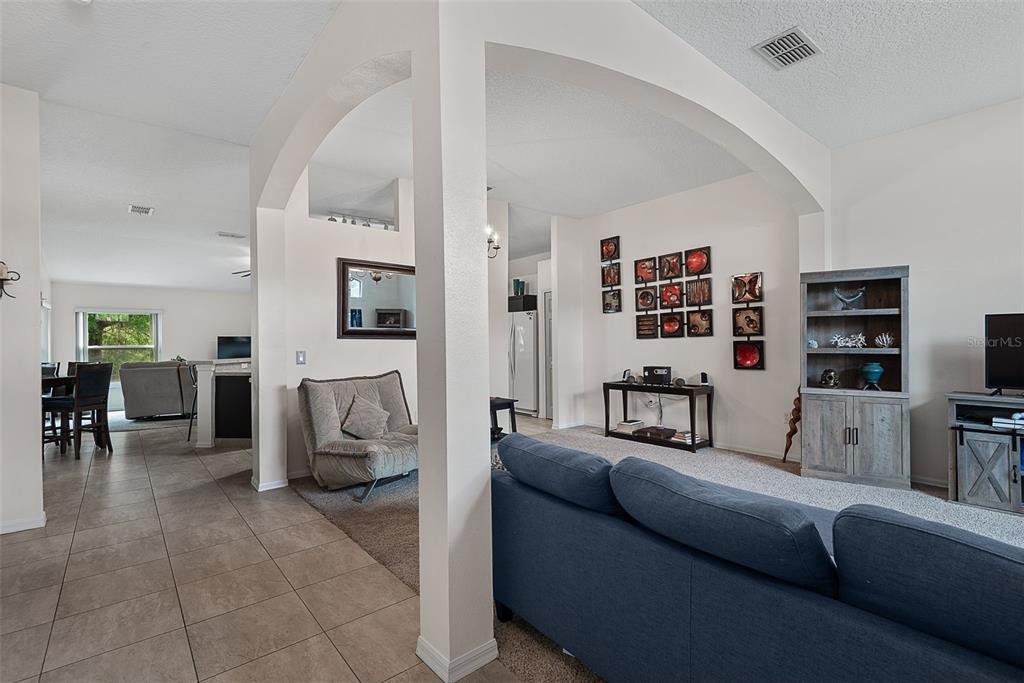 A living room features an arched entryway, tile and carpet flooring, and a blue sofa — 3 RUSSMAN LANE, PALM COAST, FL