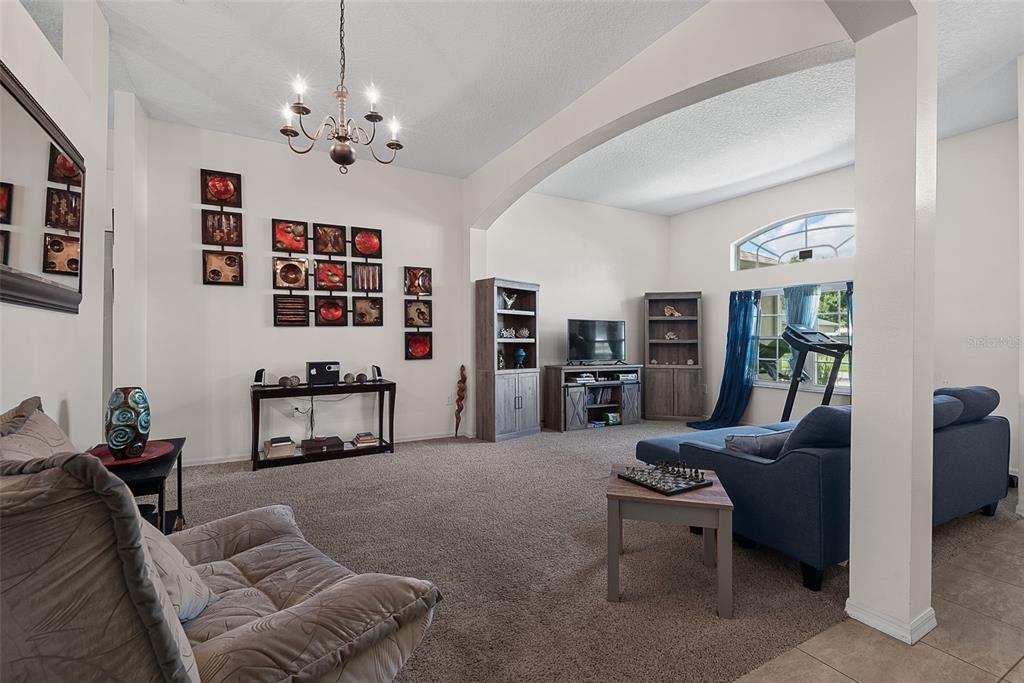 A spacious living room features carpeted flooring, a vaulted ceiling, and a large arched opening — 3 RUSSMAN LANE, PALM COAST, FL